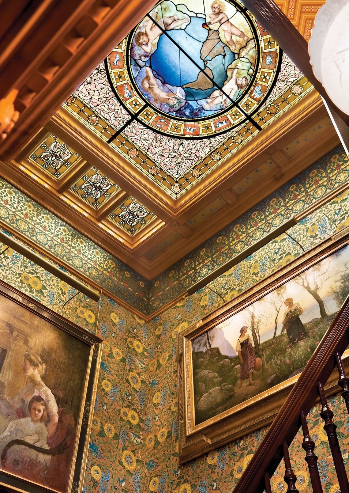 A period stained-glass lay light sporting signs of the zodiac tops the stair hall