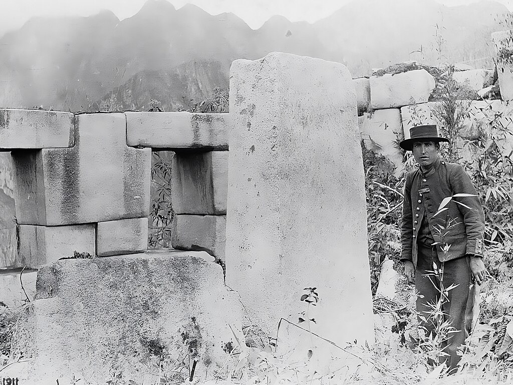 One of the photographs taken by Hiram Bingham during his first visit to Machu Picchu on July 24, 1911. On the left, in the first window from left to right (facing Huayna Picchu), is a signature inscription that reads "A. Lizárraga 1902". This signature, executed in charcoal, is attributed to Agustín Lizárraga, a Peruvian explorer and farmer, and dates back to July 14, 1902. It also shows Sergeant Carrasco, his military escort, on the right.