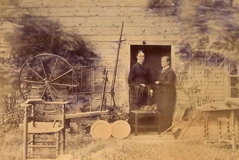 Fairbanks House 1870’s — Seen here are two of the three sisters who owned the Fairbanks House from 1843 to 1879. The eldest sister, Prudence, died first, at age 89 in 1871. These are probably the two younger sisters, Sally (1790 – 1877) and Nancy (1794 – 1879). For this photograph the sisters posed outside the Fairbanks House with some of their prized family heirlooms, along with their cat.