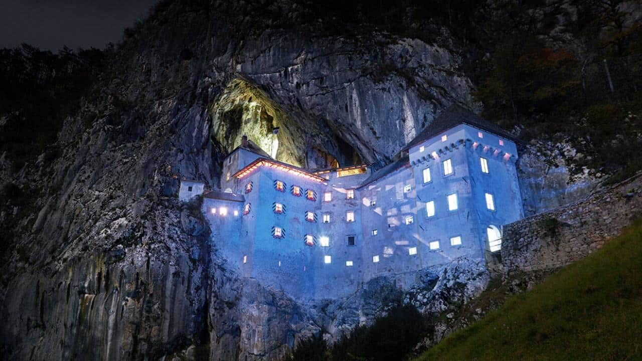 A photo of Predjama Castle taken just after sunset during the blue hour